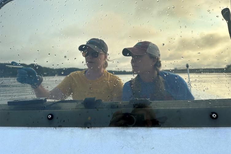克里斯汀·沃德姐妹, 左, 和劳拉·布朗驾驶着一艘船从大海湾河口驶向南尼岛附近的修复地点.