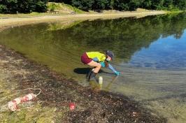 研究er Christine Bunyon collects a cyanobacteria sample from Keyser Pond in Henniker, 新汉普郡. 