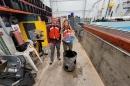 两名UNH学生研究人员将他们赢得的海洋可再生能源设备放在波浪箱前. They are wearing red life jackets.